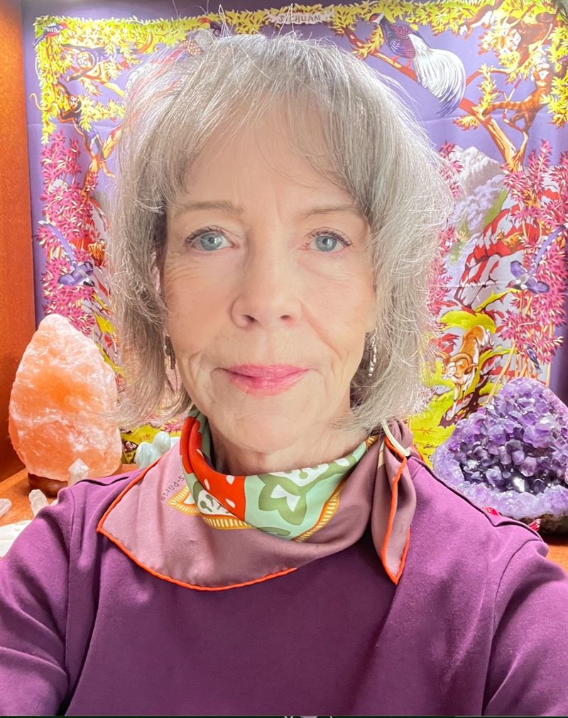 Valerie Thomas smiling, with an amethyst crystal and a salt lamp behind her